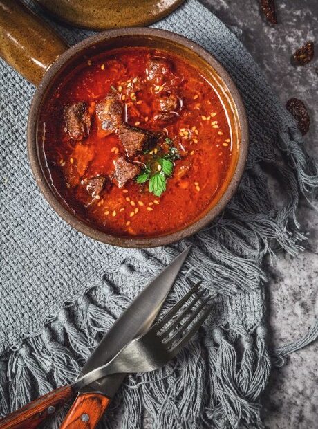 Fleisch in einem Topf geschmort, davor Besteck