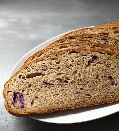 Vier aufgeschnittene Brotscheiben auf einem weißen Teller. Das Brot enthält Rotkohl