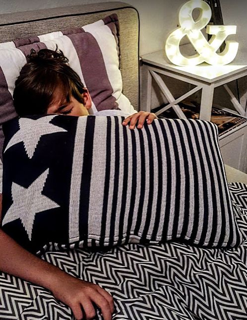 Kranker Junge liegt im Bett und hält ein Kissen vor den Körper