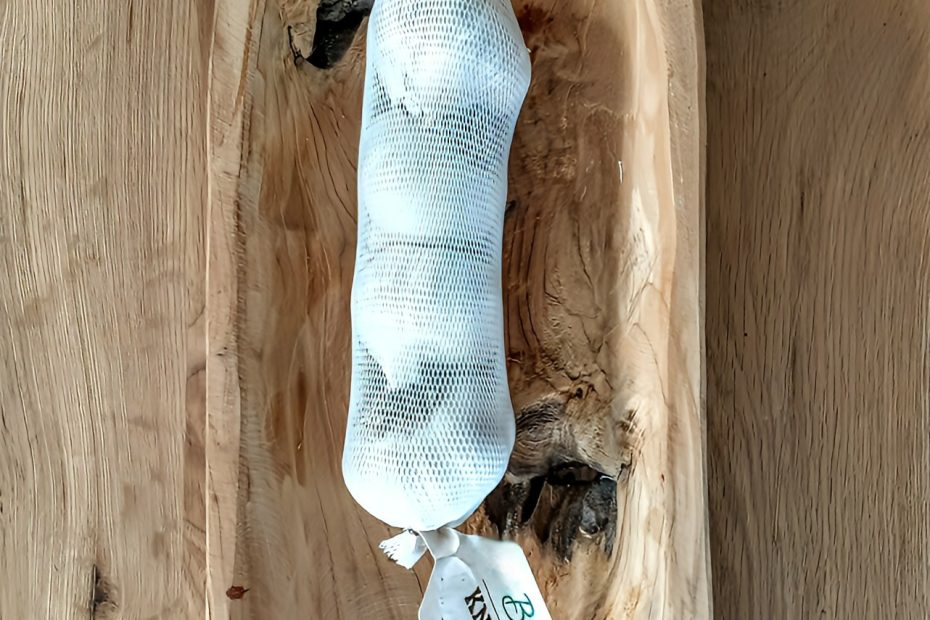 Knoblauchzehen in einem Netz, liegen in einer Holzschale